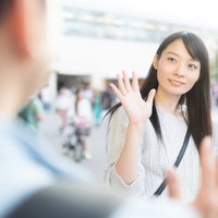 彼女と駅前で手を振って待ち合わせ、再会を喜ぶの写真