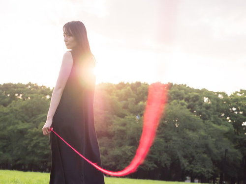 私たちは赤い糸で結ばれているの（ウフフ）緑の丘陵を背に立つ女性