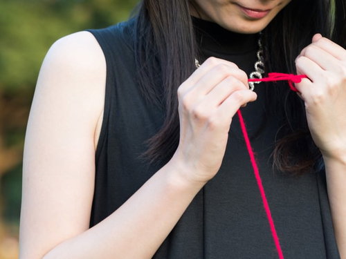 赤い糸で結ばれた女性の手元、運命の出会いを表現