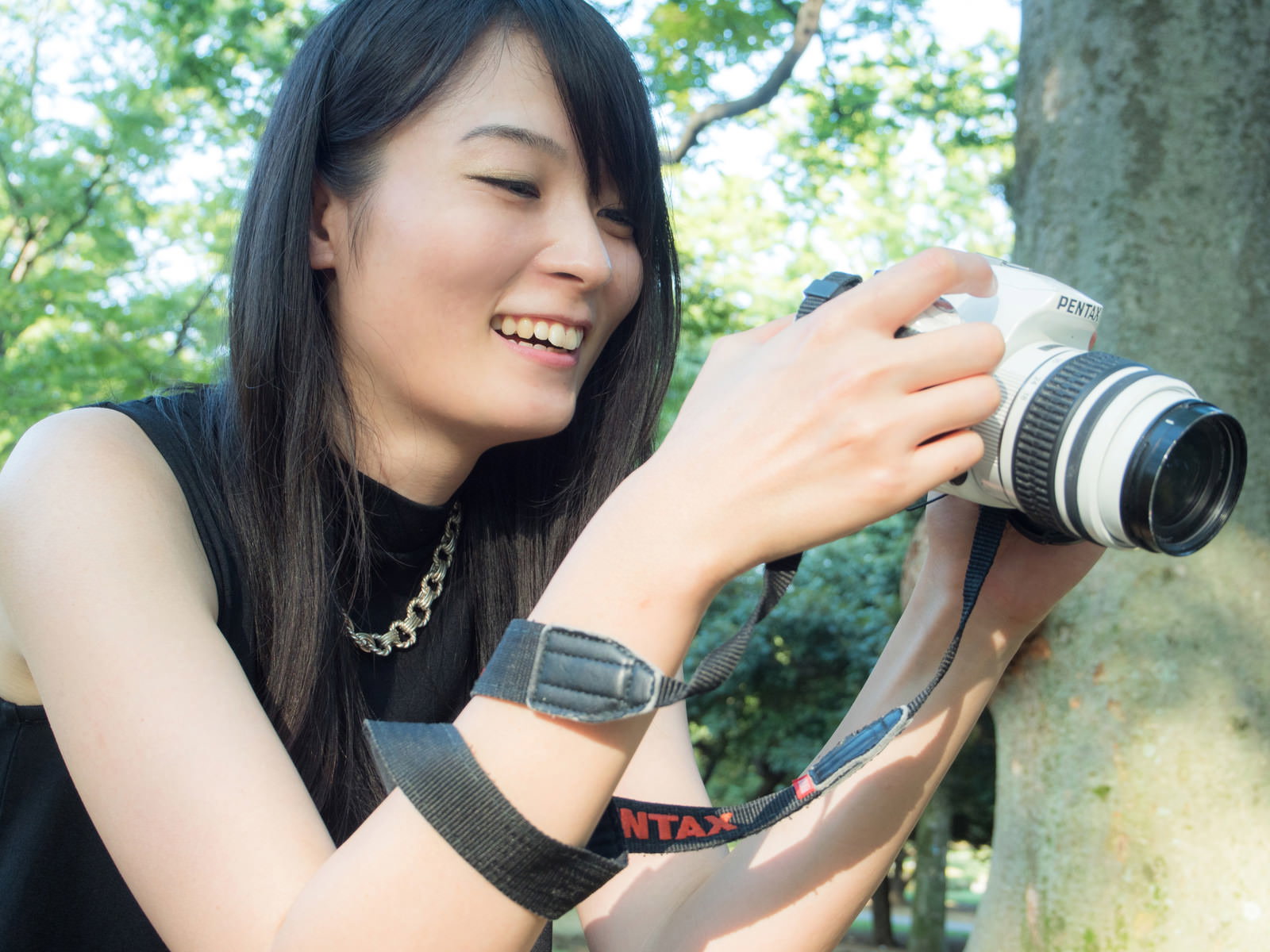 PENTAXの一眼レフで撮影後の写真を確認して笑う女性［モデル：たけべともこ］