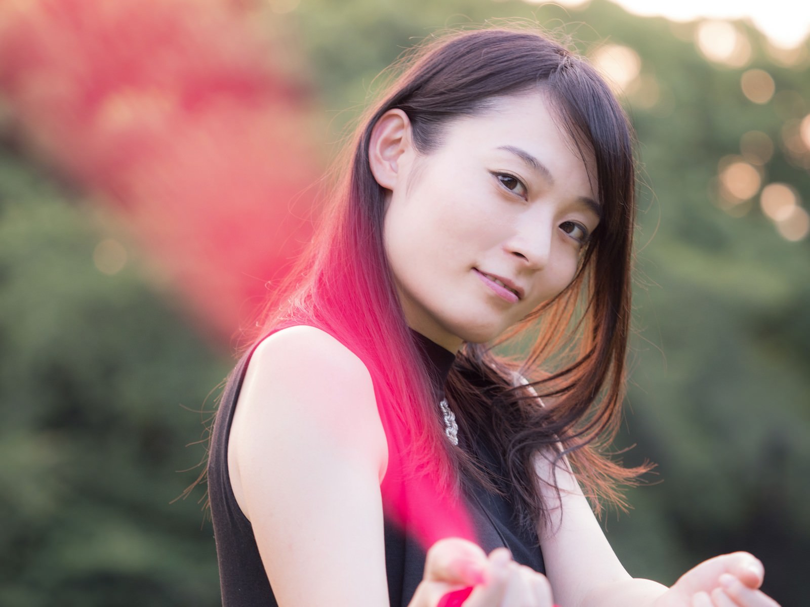 ピンクのトップスを着た黒髪の女性が背中を向け、うつむきながら横を向いている写真［モデル：たけべともこ］