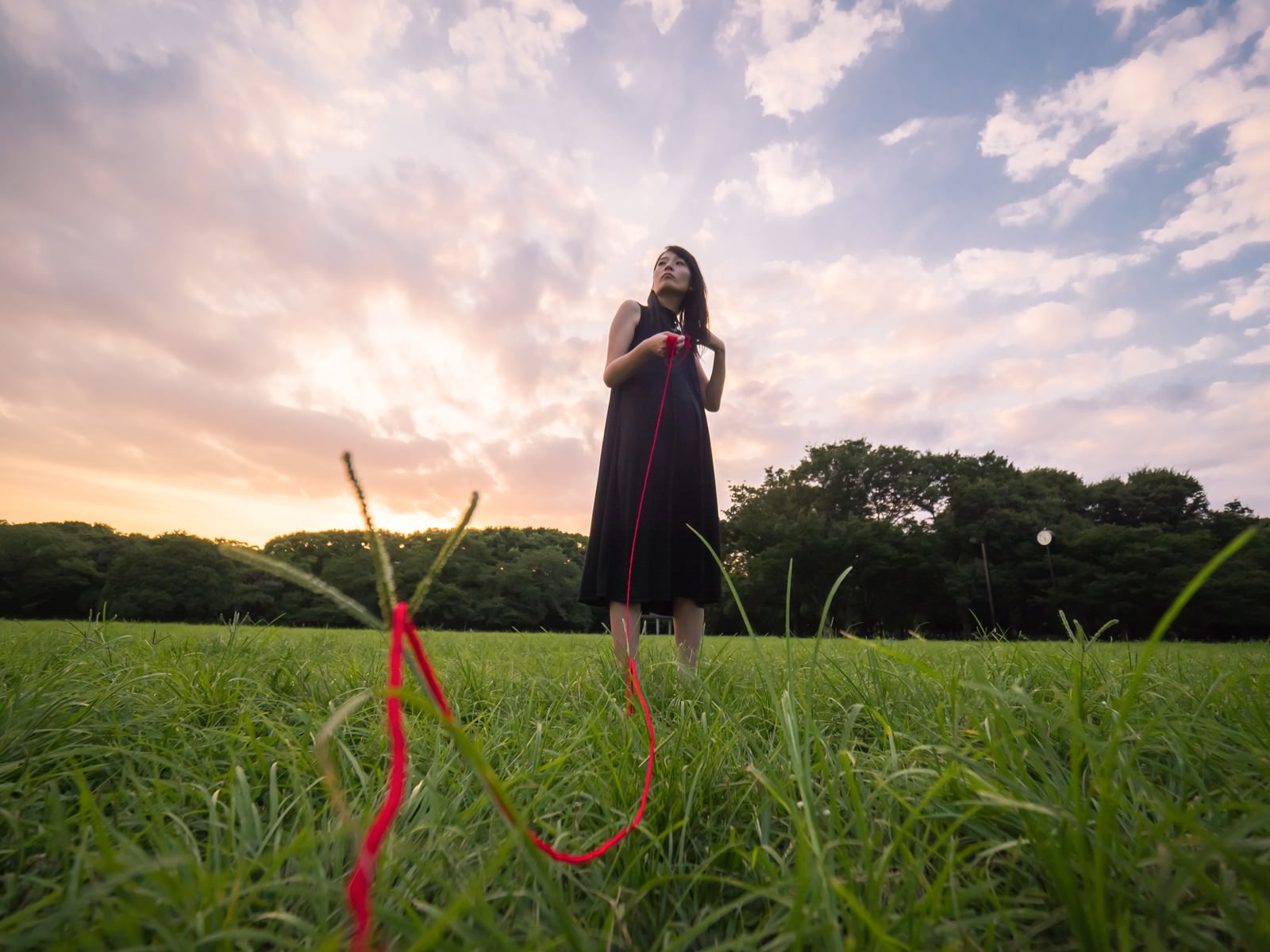 夕暮れの公園で赤い糸を持つ女性のシルエット［モデル：たけべともこ］