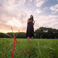 彼女に赤い糸で繋がれた彼氏の目線で見た草原と空の写真
