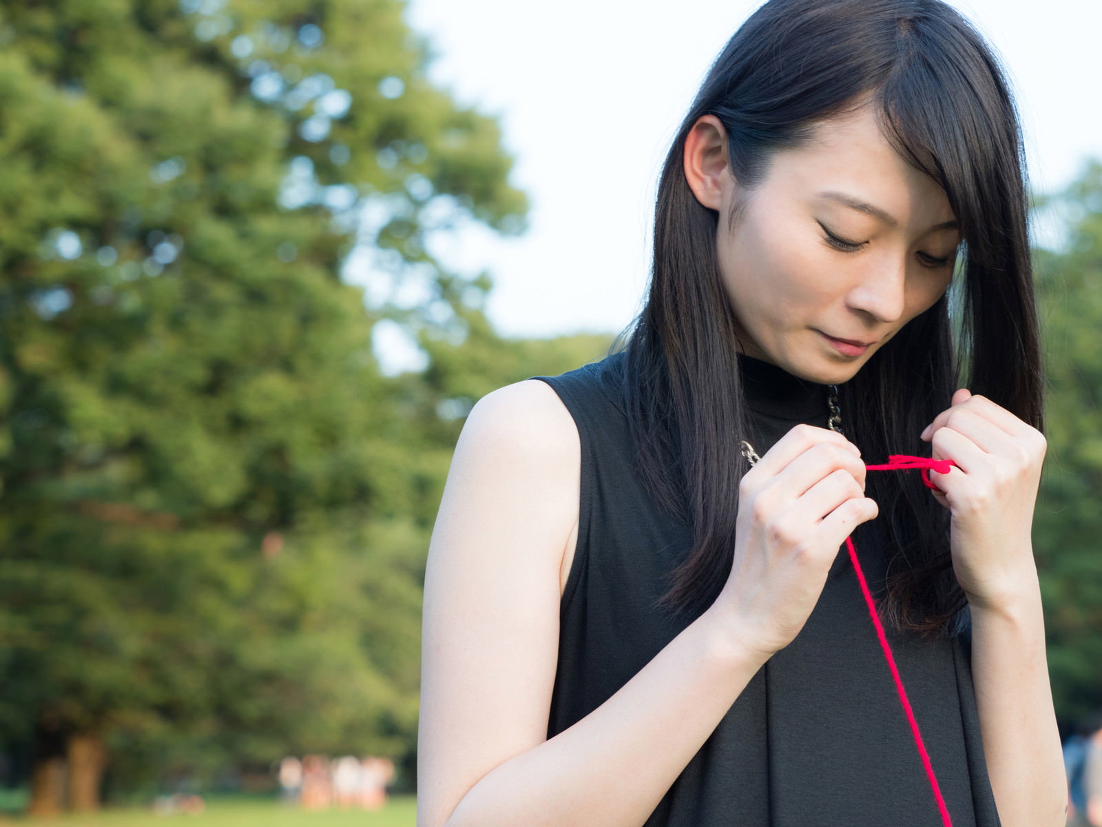 赤い糸を結び直す女性の手元［モデル：たけべともこ］