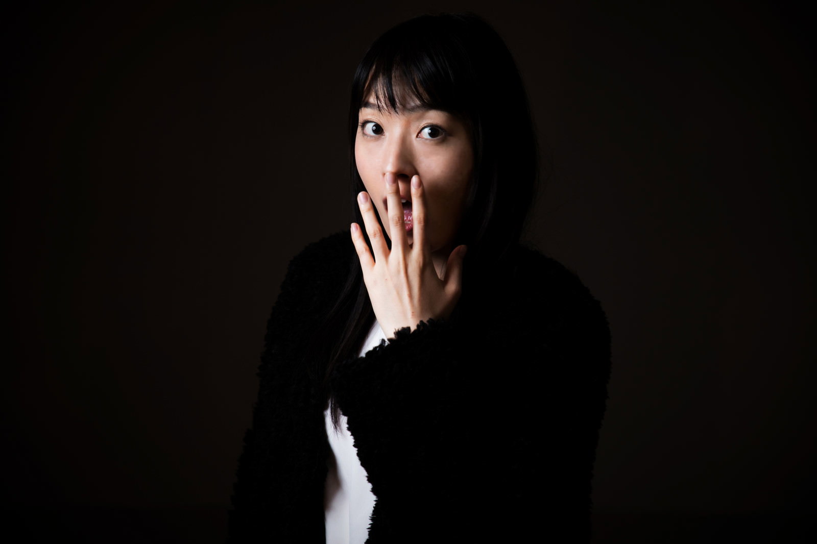 驚いて両手で口を覆う女性［モデル：たけべともこ］