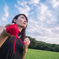 赤い糸を握りしめる失恋女子が青空を見上げるの写真