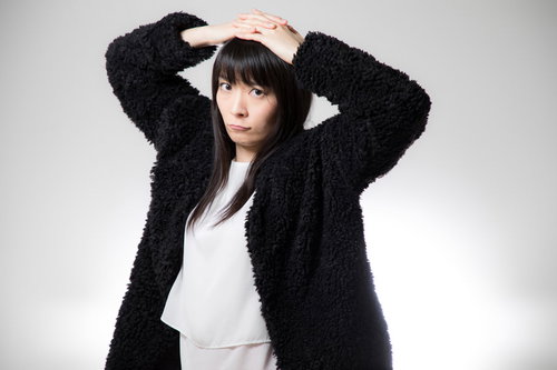 黒いモコモコカーディガンを着た困った顔の女性