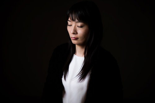 目を閉じて立ったまま瞑想や思考に集中する女性