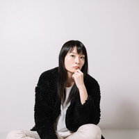 黒いカーディガンで頬に手を当てて考える冷静な女性の写真