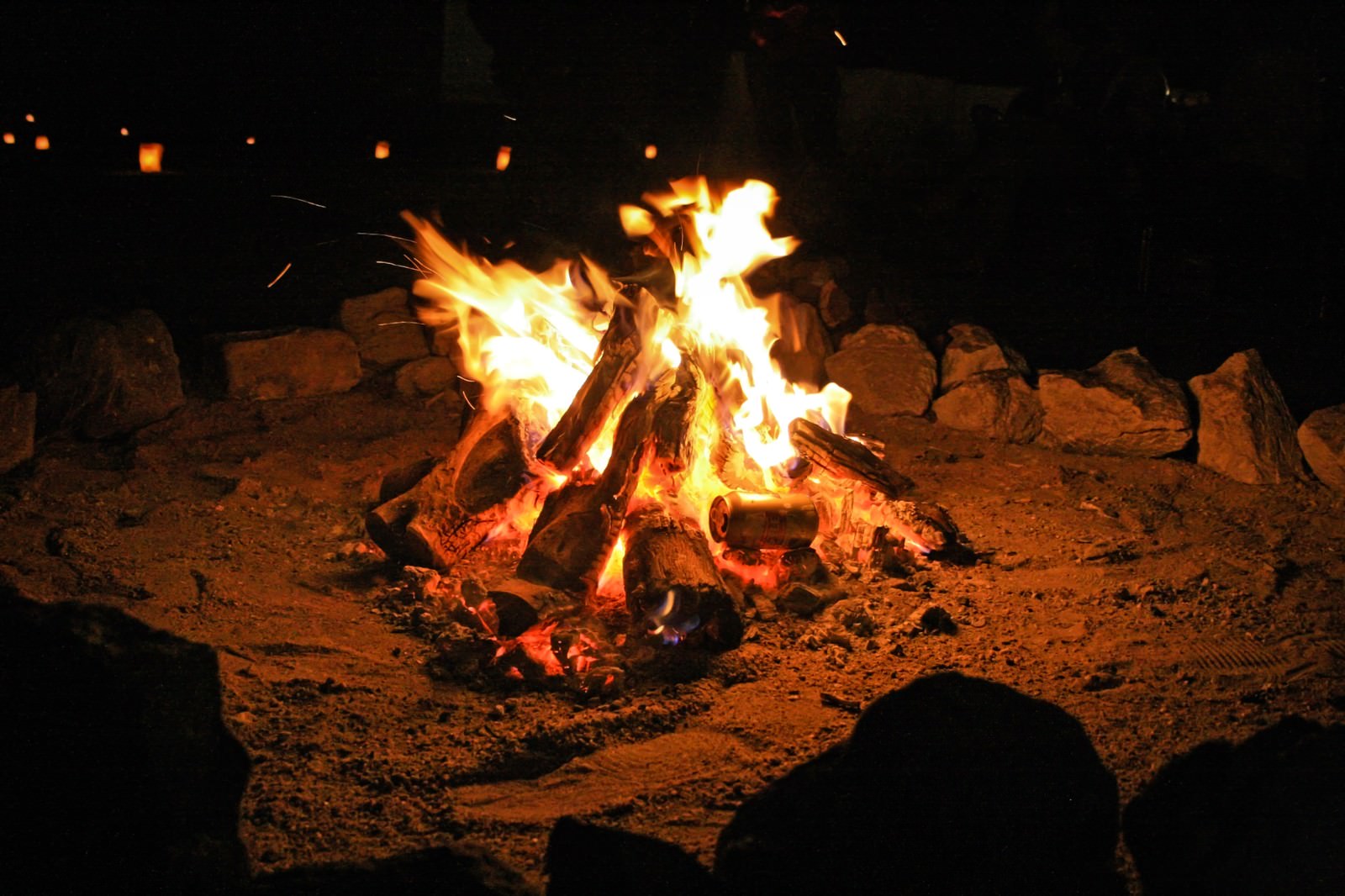 夜間に石で囲まれた焚き火の炎が上がっている