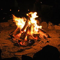 夜間の焚き火を囲む石積みの写真
