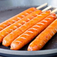 炭火の上で焼き色がつくバーベキューのフランクフルトの写真