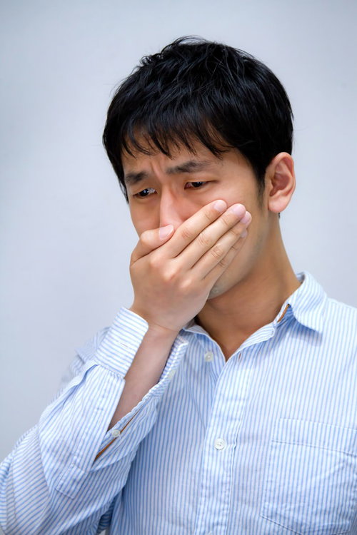 白い背景の前で目頭を押さえて泣きそうな表情の男性