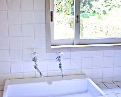 蛇口とステンレスの排水口がある白いタイルの流し台