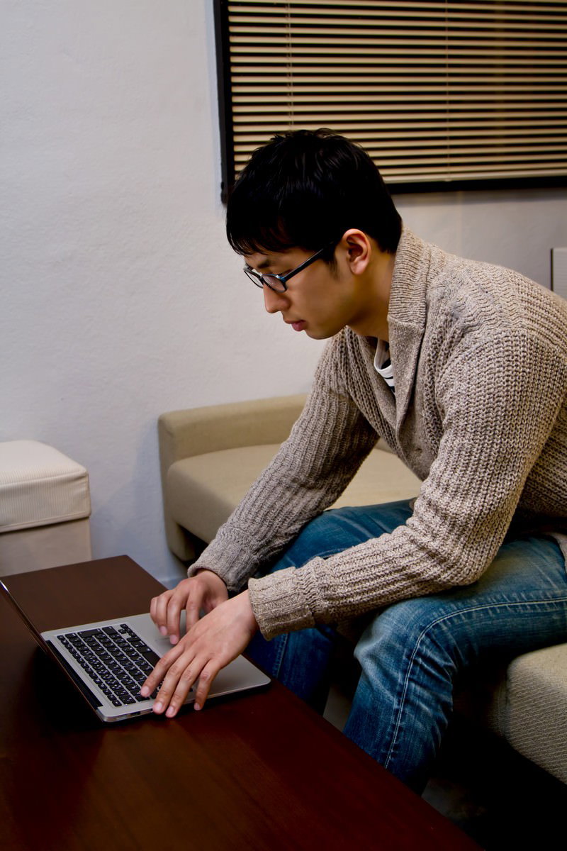 ソファーでPCを操作する男性［モデル：大川竜弥］