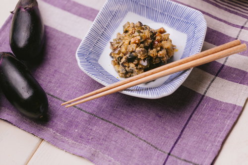 ナスを使った味噌炒め、木の箸が添えられた和食の副菜
