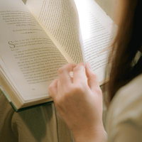 自然光の下で洋書をページめくりする女性の手元の写真