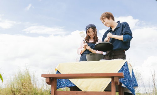 晴れた空の下で夫婦でダッチオーブン料理を楽しむアウトドア調理