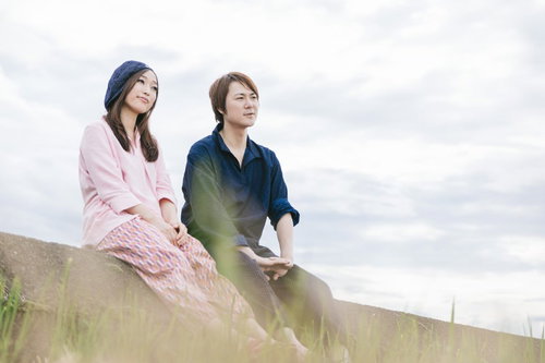 農作業を終えて草土手で休憩するもんぺ姿の若い夫婦