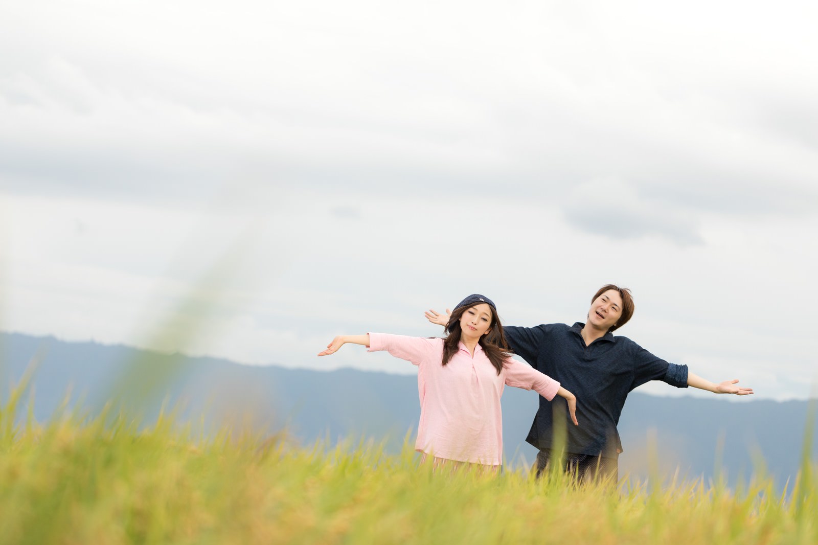 大刀洗町の稲穂の中で両手を広げる若い夫婦［モデル：五十嵐夫妻］