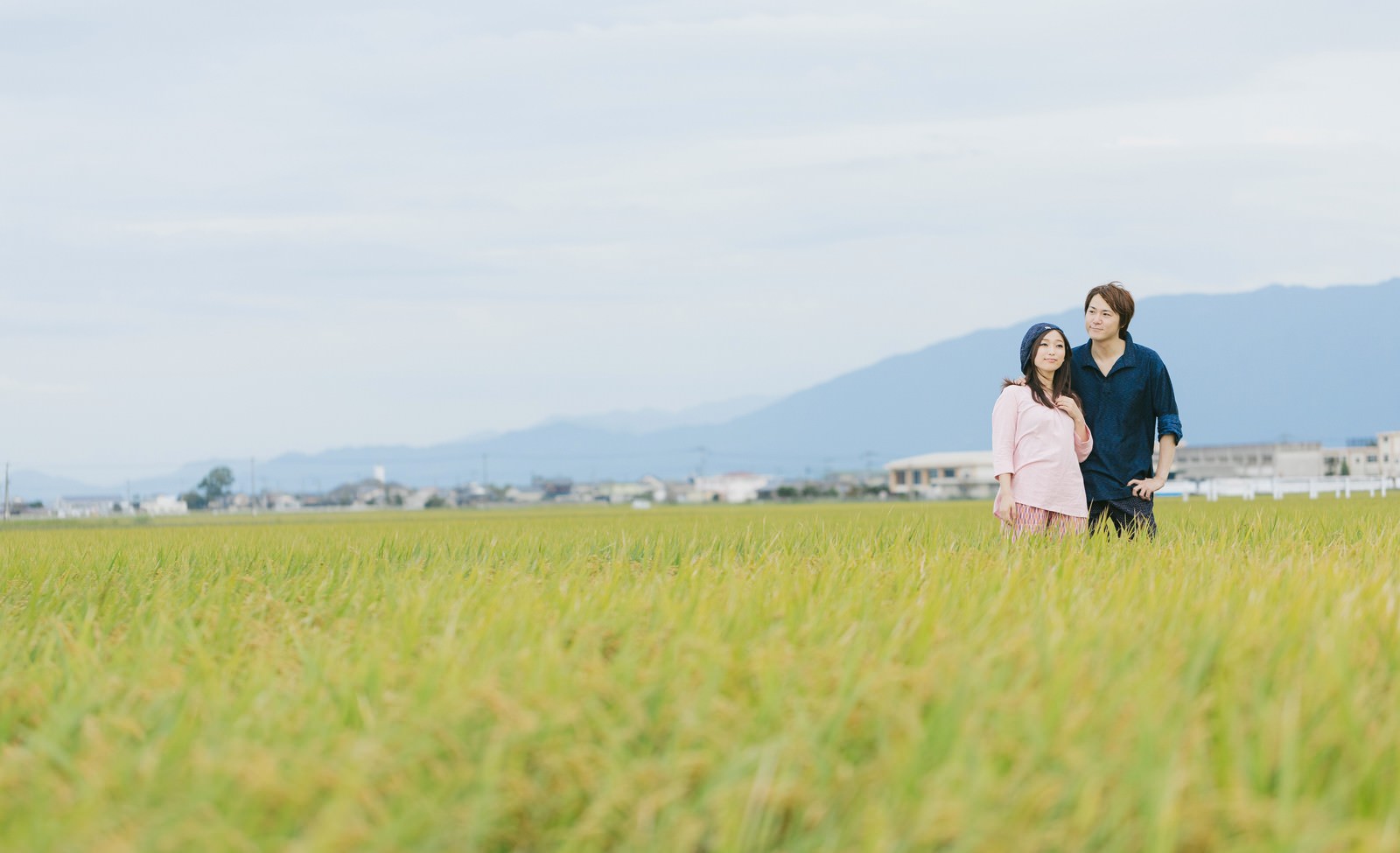 秋の大刀洗の田んぼに立つ夫婦と実った稲穂［モデル：五十嵐夫妻］