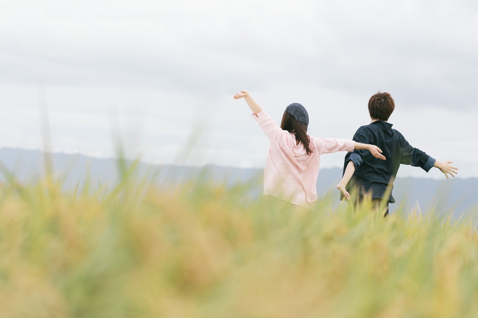 秋の稲穂が広がる大刀洗の田園で両手を広げる夫婦の後ろ姿［モデル：五十嵐夫妻］