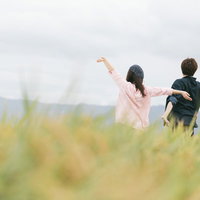 大刀洗の田園で両手を広げる農作業姿の夫婦の写真