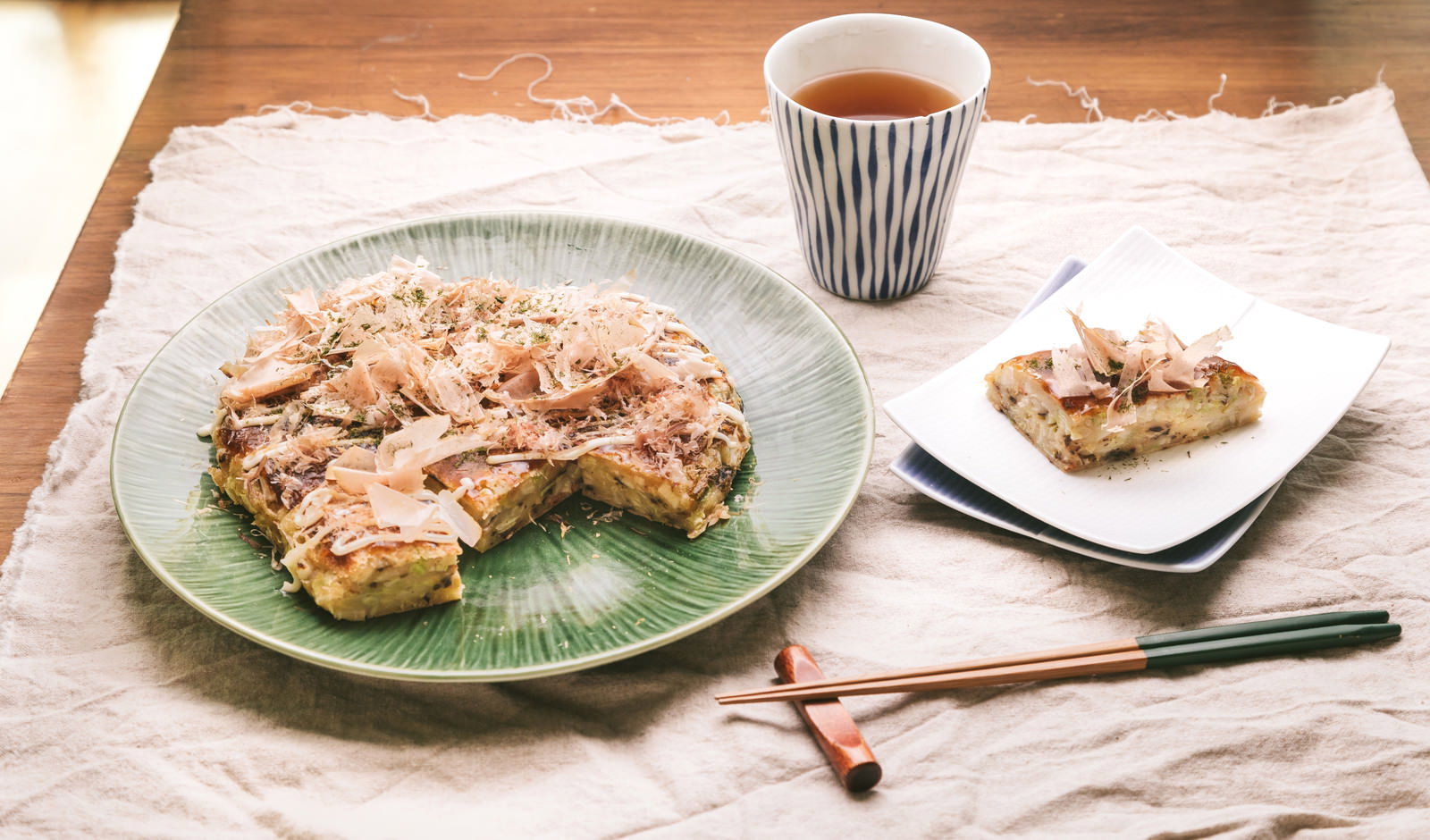 鰹節と青のりをのせたお好み焼きとお茶の食卓