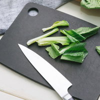 黒いまな板で小松菜をざく切りにする調理工程の写真