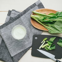 黒いまな板で小松菜をカットしてスムージー作りの写真