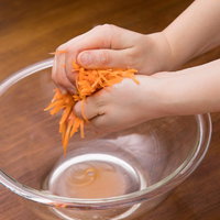 にんじんの千切りをガラスボウルで塩もみする下ごしらえの写真