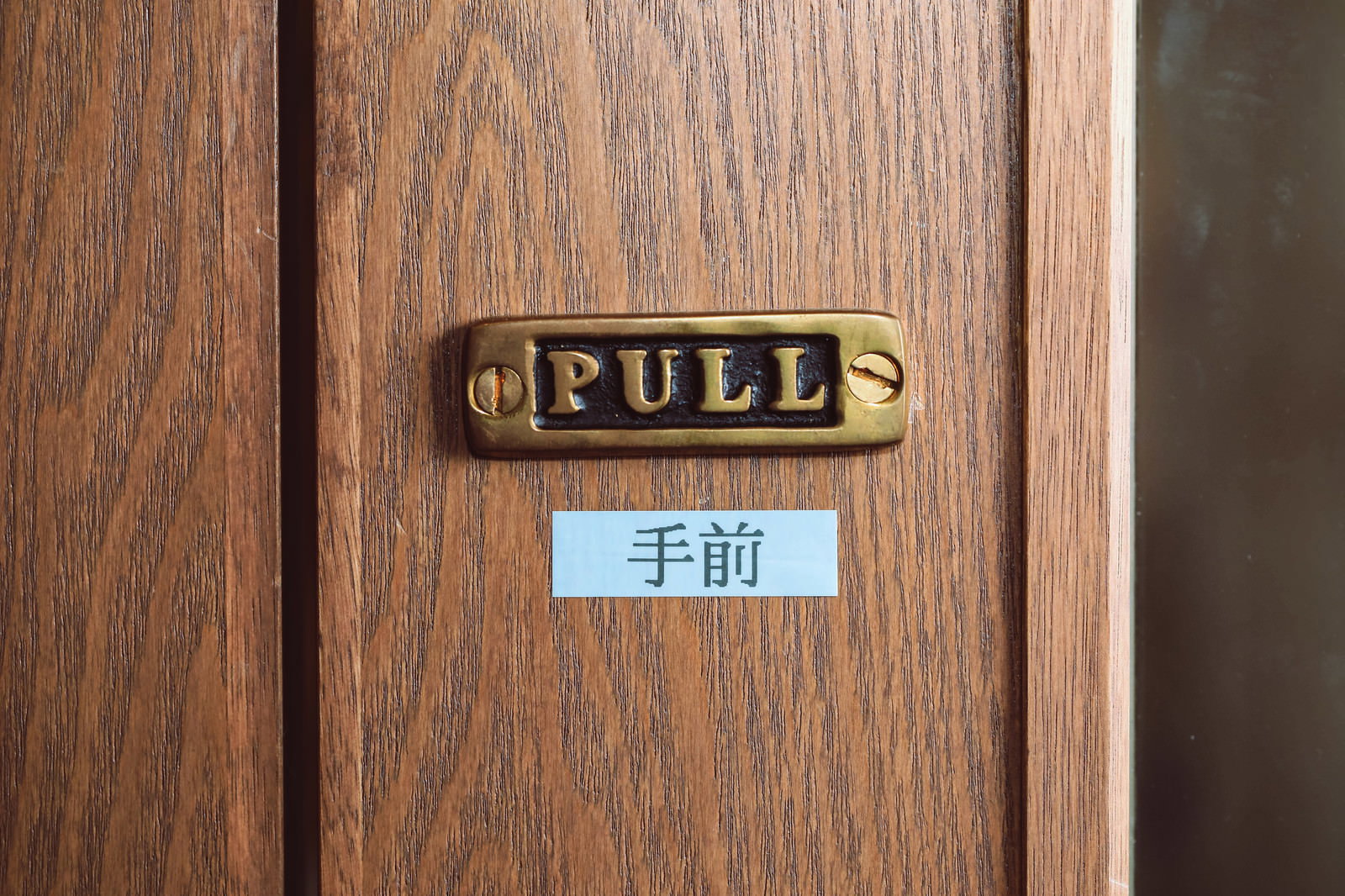 木製ドアに取り付けられたPULLプレートとテプラ