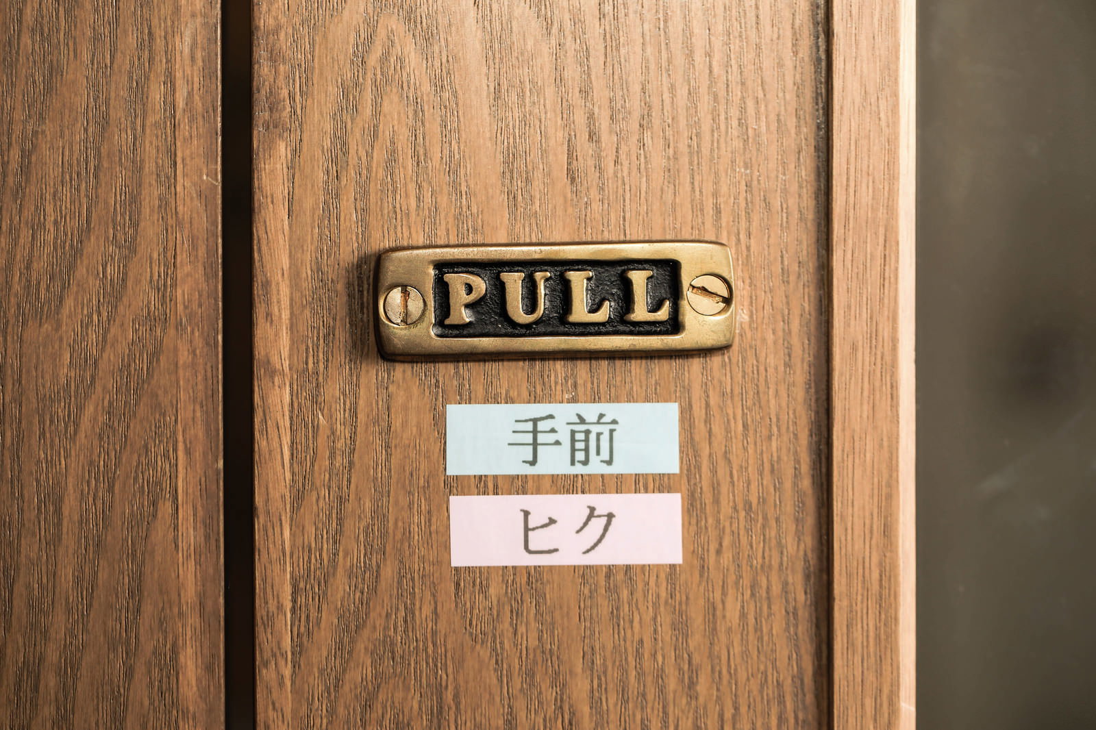 木製ドアに金色のPULLプレートとテプラで「手前」「ヒク」と表記