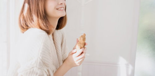 焼き菓子を手に持って微笑む茶色い髪の女性