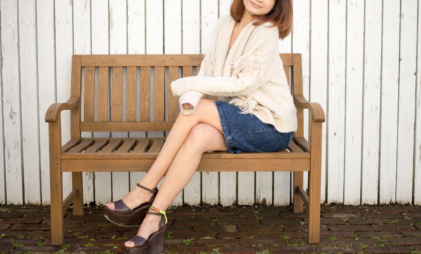 木製ベンチに座ってリラックスしている若い女性