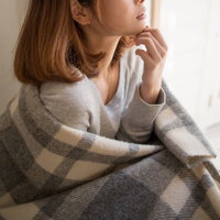 チェック柄のブランケットを肩に羽織る女性の写真