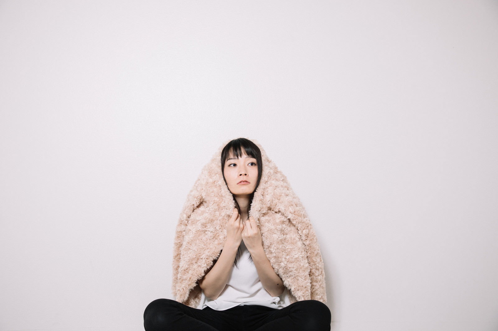 毛布を羽織り床に座って上を見上げる女性［モデル：たけべともこ］
