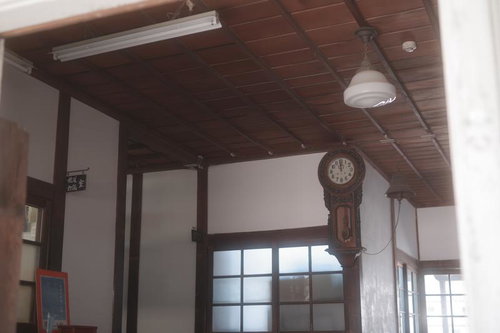 暮れゆく放課後の廊下に掛かる古い柱時計と木造校舎