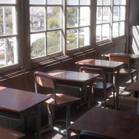 窓からの採光が入る放課後の教室と学習机の風景の写真