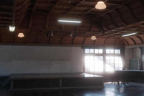 光が差し込む旧遷喬尋常小学校の講堂、木造校舎の歴史的建築空間