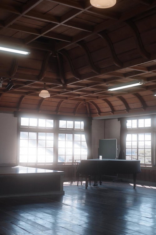 光差し込む旧遷喬尋常小学校講堂の黒板と木造天井構造