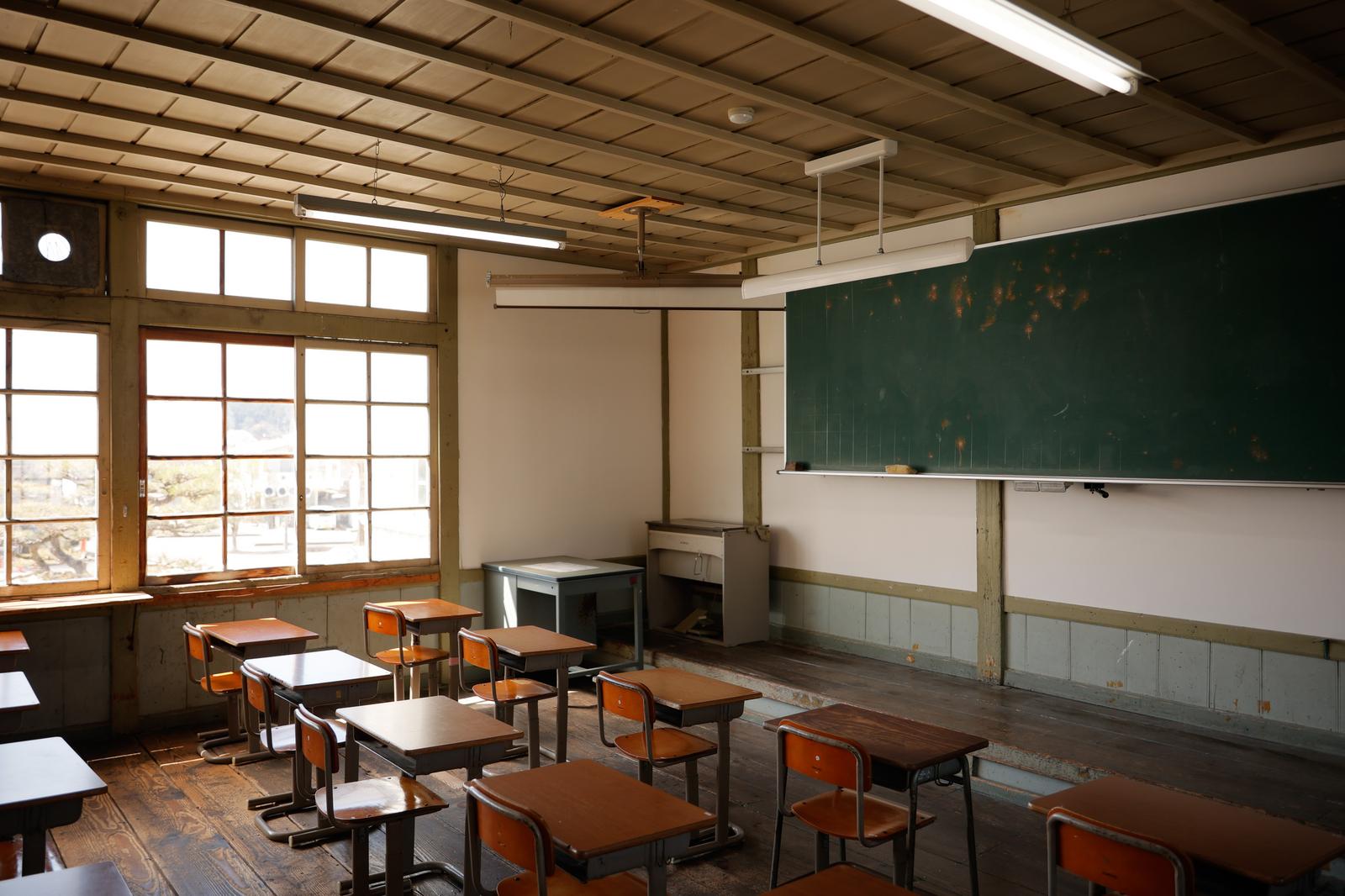 放課後の教室で窓から光が差し込む学習机と黒板
