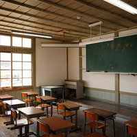 放課後の教室で黒板と学習机に降り注ぐ窓からの光の写真