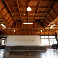 旧遷喬尋常小学校の講堂と折り上げ格天井、ピアノと木製フローリングの写真