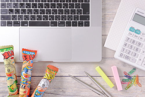 デスク上に置かれた付箋、ペン、文房具とうまい棒