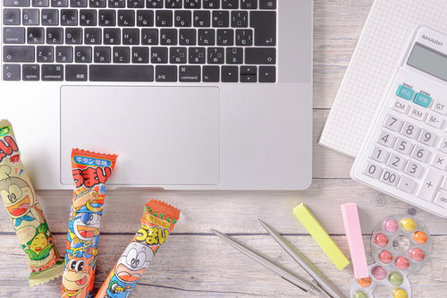 うまい棒を食べながら経理作業をするデスク