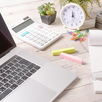デスクに置かれた文房具とクリップ、ノートパソコンの写真