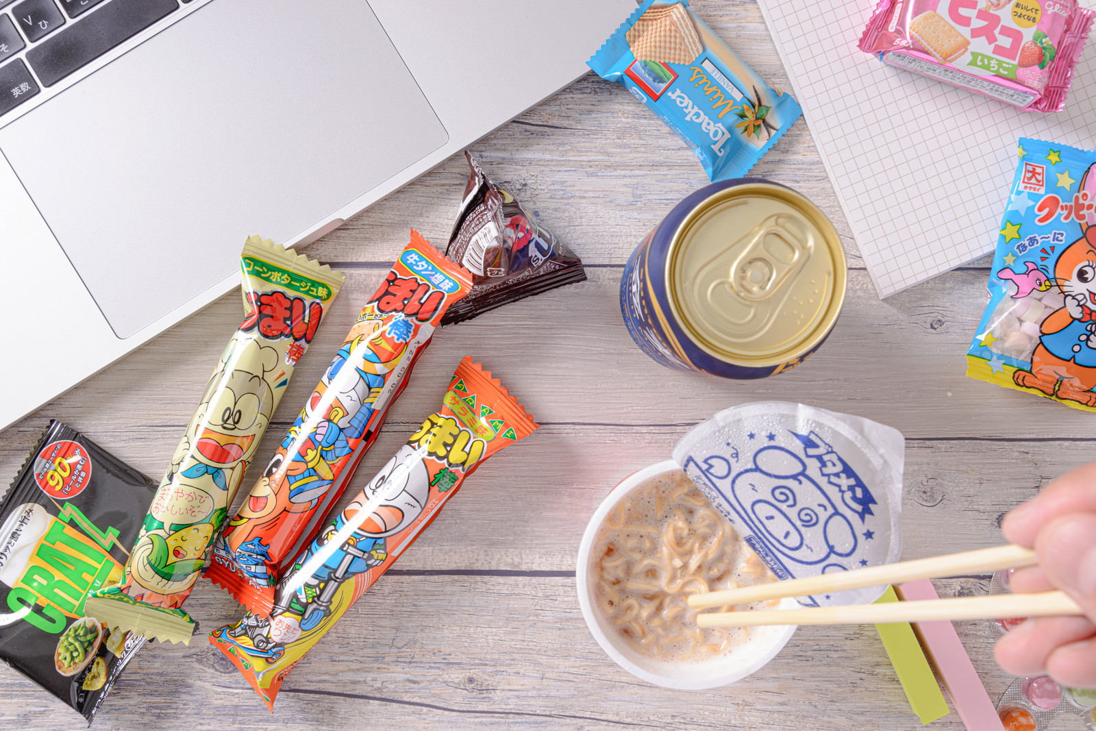 机の上にブタメンとお菓子、缶ビールが置かれた様子