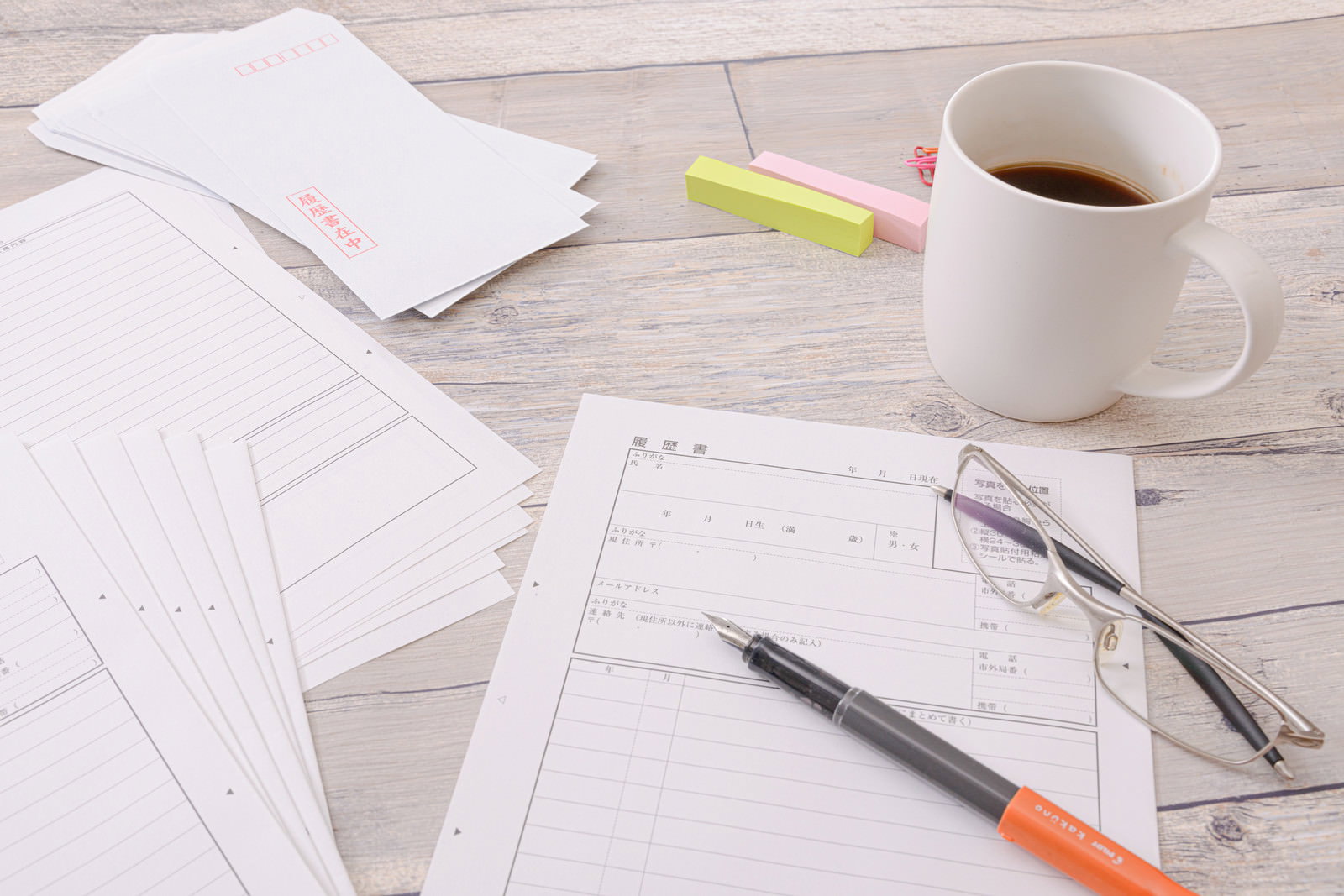 Blank resume, pen, glasses, and coffee cup placed on a wood-textured desk