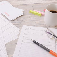 記入する前の履歴書の山とデスク周りの文房具の写真